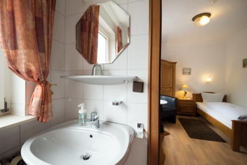 a bathroom with a sink and a bedroom with a bed at Hotellerie Gasthaus Schubert in Garbsen