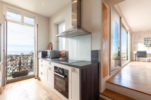 Il comprend une cuisine équipée d'une cuisinière. four supérieur à côté d'une fenêtre dans l'établissement Roucas Blanc Vue Mer Exceptionnelle, à Marseille