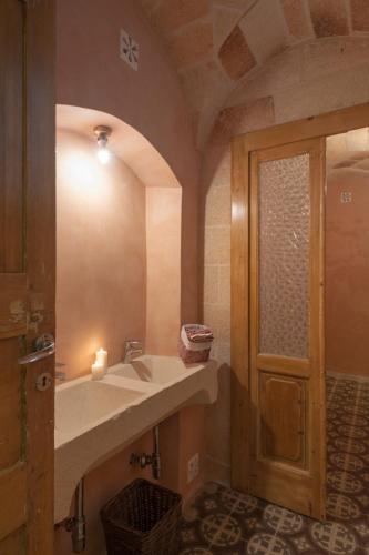 a bathroom with a sink and a door with a candle at Borgoterra in Martano