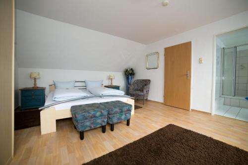 a white bedroom with a bed and a chair at Hotellerie Gasthaus Schubert in Garbsen