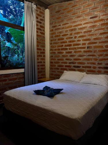 a bed in a room with a brick wall at Hostería RIVER PARADISE in Río Negro
