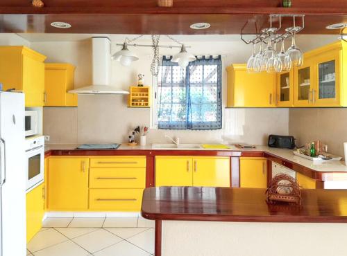 a kitchen with yellow cabinets and a table in it at Maison charmante à Petit-Bourg + Jardin in Petit-Bourg