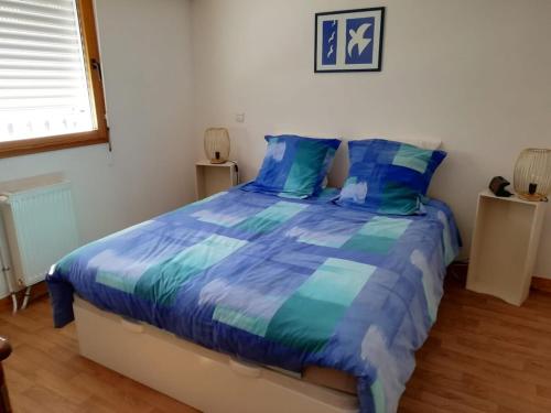 une chambre avec un lit avec des draps bleus et une fenêtre dans l'établissement appart de charme -proche du jardin Dior, à Granville