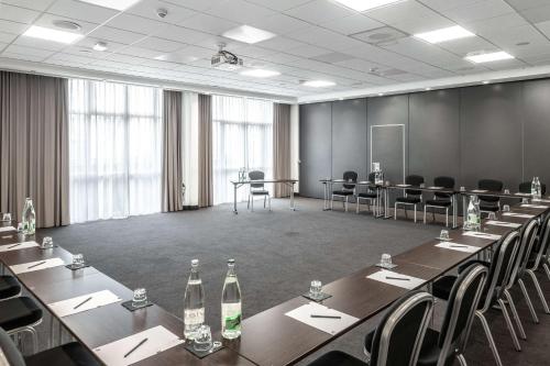 a meeting room with long tables and chairs and bottles at pentahotel Paris Charles de Gaulle in Roissy-en-France