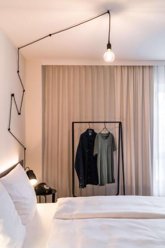 a bedroom with a bed and a shirt on a rack at pentahotel Wiesbaden in Wiesbaden