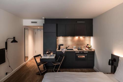 a kitchen with black cabinets and a table and chairs at pentahotel Wiesbaden in Wiesbaden
