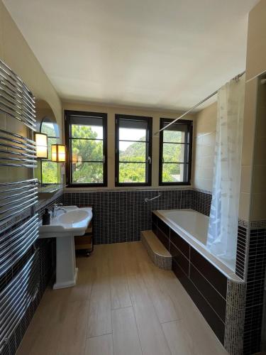 une grande salle de bain avec une baignoire et un lavabo dans l'établissement Le gîte de l 'instit', à Peyraud