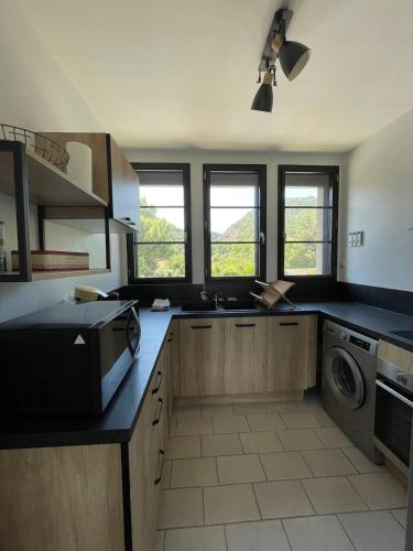 une cuisine avec un évier et une machine à laver dans l'établissement Le gîte de l 'instit', à Peyraud