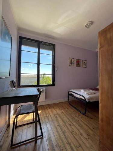 une chambre avec un lit, un bureau et une fenêtre dans l'établissement Le gîte de l 'instit', à Peyraud