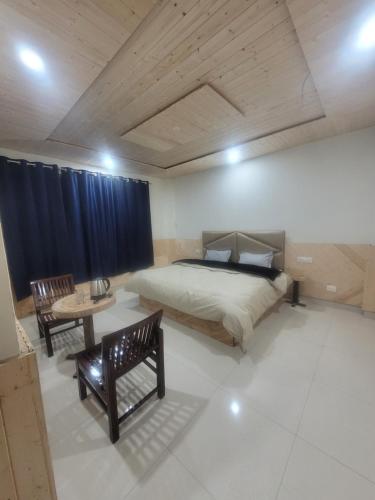 a bedroom with a bed and a table and chairs at Whoopers Hostel Kasol in Kasol