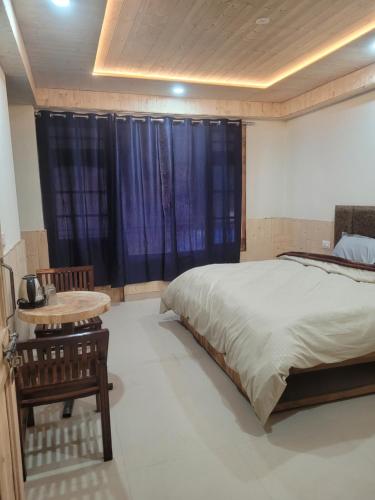 a bedroom with a bed and a table and a window at Whoopers Hostel Kasol in Kasol