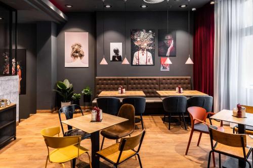a restaurant with tables and chairs and pictures on the wall at Pentahotel Rostock in Rostock
