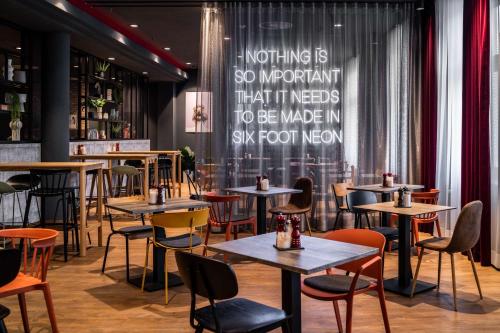 a restaurant with tables and chairs and a chalkboard at Pentahotel Rostock in Rostock
