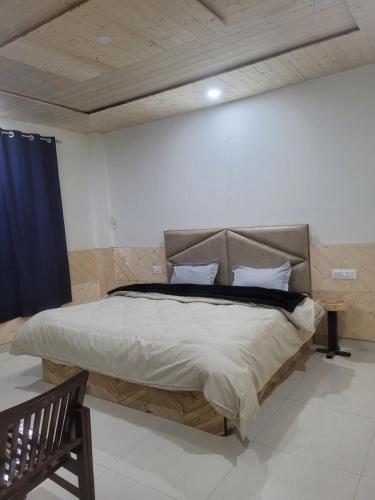 a bedroom with a large bed with a blue curtain at Whoopers Hostel Kasol in Kasol