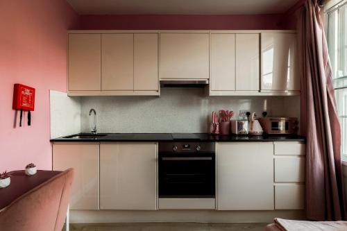 a kitchen with white cabinets and a black oven at Gloucester Place Studios in London