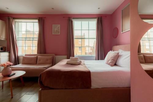 a bedroom with pink walls and a bed and a couch at Gloucester Place Studios in London