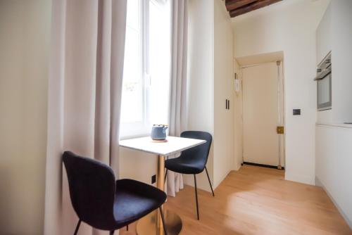 une table et des chaises dans une pièce avec une fenêtre dans l'établissement CIA - Studio by Arc de Triomphe, à Paris