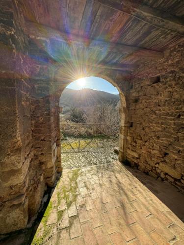 an arch in a stone wall with the sun shining through it at Il borgo di Firenzuola Camere con camino in Acquasparta