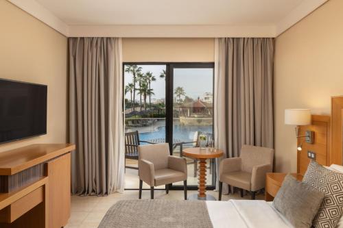 a hotel room with a bed and a television at Atlantica Golden Beach Hotel - Adults Only in Paphos