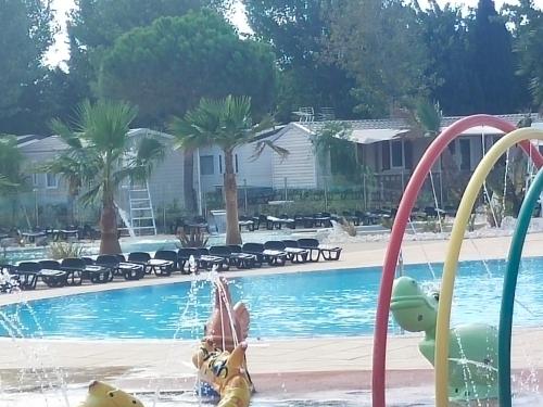 un niño jugando en el agua en una piscina en MOBIL HOME l'ETOURNEAU, en Valras-Plage