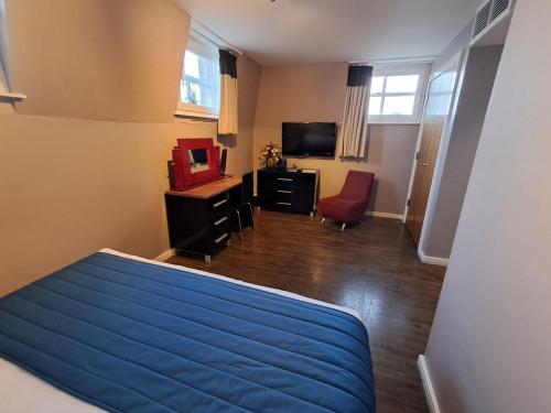a bedroom with a blue bed and a television at The Royal Hotel Cardiff in Cardiff