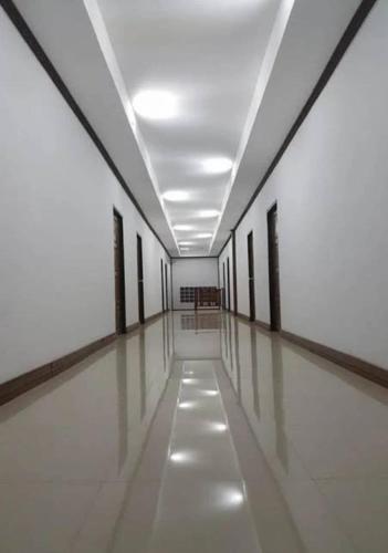 a long hallway with white walls and a long white floor at JP Place in Ban Ru Yai