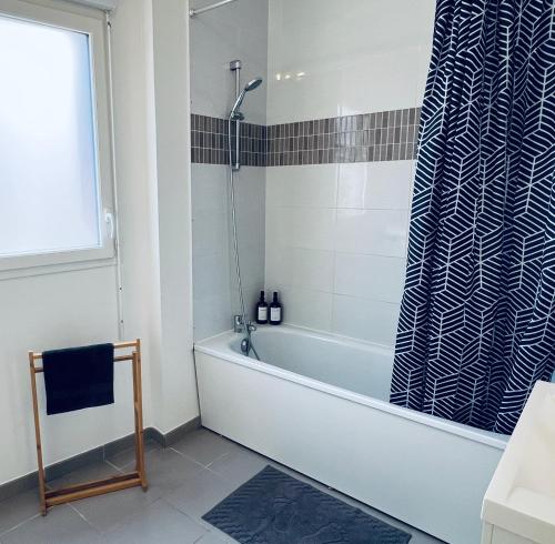 La salle de bains est pourvue d'une baignoire et d'un rideau de douche. dans l'établissement Duo Verde Du style et de la Luminosité Famille Disney Parking Patio, à Montévrain