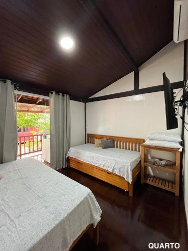 a bedroom with two beds and a television in it at Refúgio em Barreirinhas Chalé in Barreirinhas