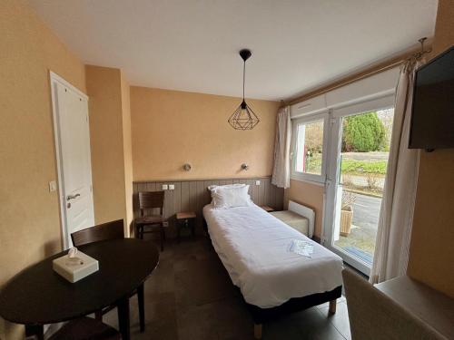 a bedroom with a bed and a table and a window at BRIT HOTEL Lannion-Perros Guirec in Lannion
