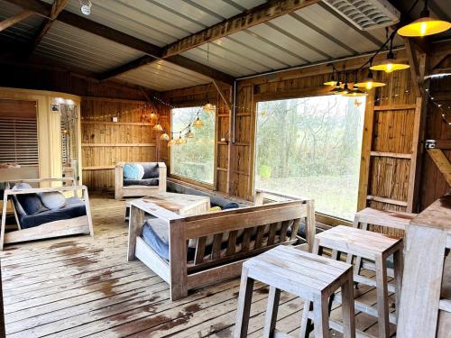une véranda dans une cabane en bois avec des bancs et des tables dans l'établissement La Lande d'Ouée - Sauna & Convivialité, à Saint-Aubin-du-Cormier