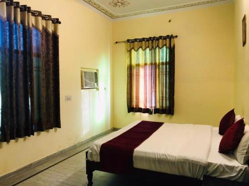 a bedroom with a bed and two windows at Hotel Green Haveli - A Heritage and Hill View Hotel , Pushkar in Pushkar