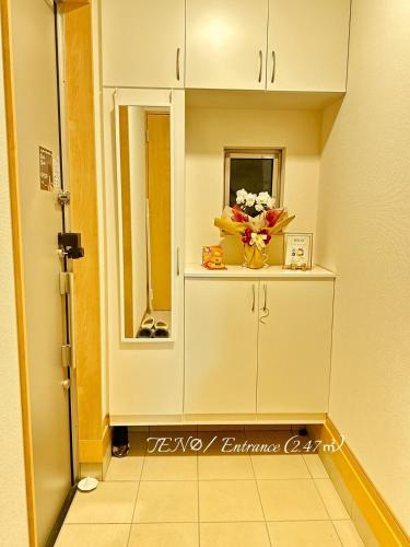 a hallway with a cabinet with a vase of flowers on it at Ten10 in Nagoya
