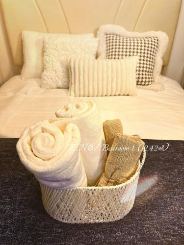 a basket filled with towels on top of a bed at Ten10 in Nagoya