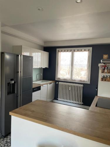 une cuisine avec un réfrigérateur et un plan de travail dans l'établissement Grand appartement avec balcon et 2 chambres, à Montluçon