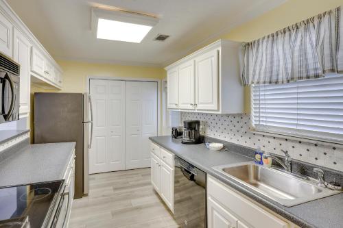a kitchen with white cabinets and a stainless steel refrigerator at 3 Mi to St Simons Beach Gem with Pool Access and Deck in Saint Simon Mills
