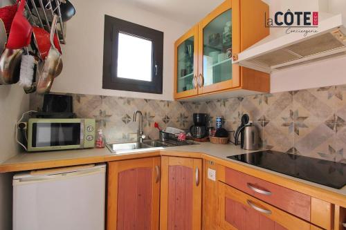 La cuisine est équipée de placards en bois, d'un évier et d'un four micro-ondes. dans l'établissement Le clos des pins, à Sausset-les-Pins