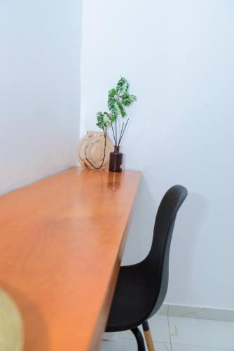 a wooden table with a black chair and a plant at Grand Appartement de 2 chambres - Résidence Sabyra in Cocody