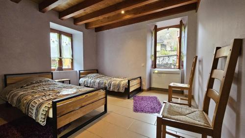 a bedroom with two beds and a chair and windows at Maison du meunier in Soursac