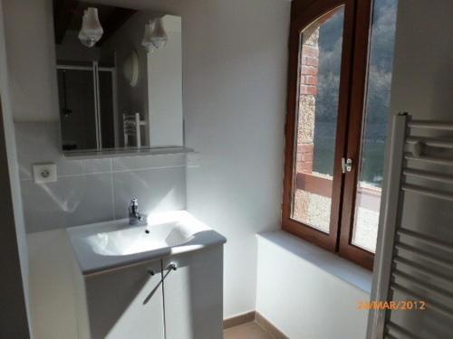 a white bathroom with a sink and a window at Maison du meunier in Soursac
