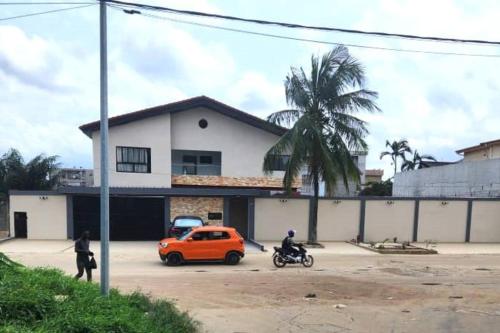an orange car parked in a parking lot next to a building at Grand Appartement de 2 chambres - Résidence Sabyra in Cocody