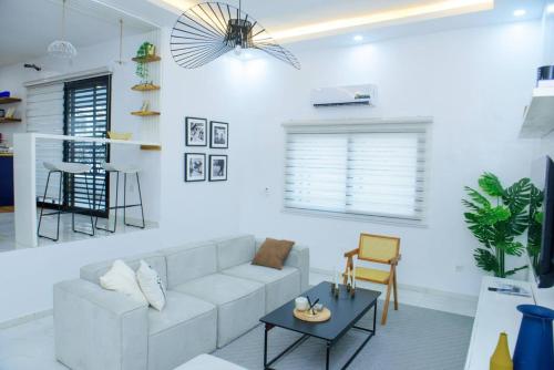 a white living room with a couch and a table at Charmant 3 pieces Riviera Palmeraie - Residence Sabyra in Cocody