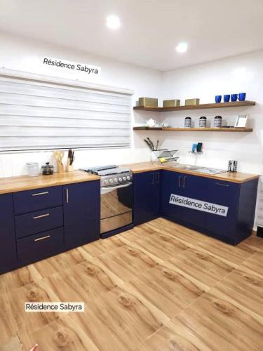 a kitchen with blue cabinets and a wooden floor at Charmant 3 pieces Riviera Palmeraie - Residence Sabyra in Cocody