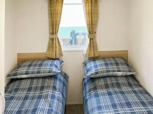 Dos camas en una habitación con ventana. en Holiday Home by the river Nidd 6, en Knaresborough