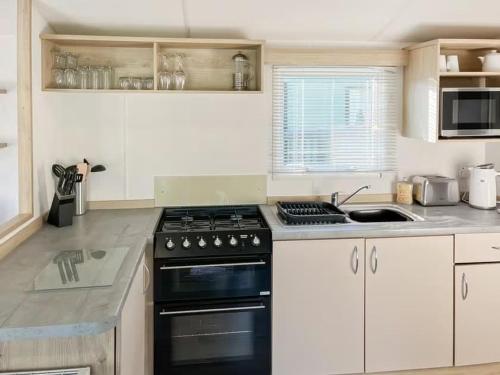 Una cocina con gabinetes blancos y un horno de estufa. en Holiday Home by the river Nidd 6, en Knaresborough