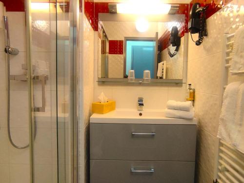 a bathroom with a sink and a shower with a mirror at Contact Hotel Be Guest Limoges Sud in Limoges