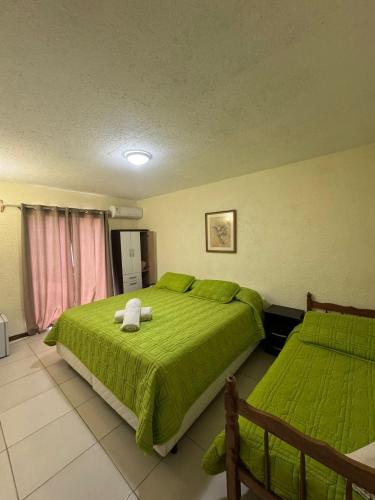a bedroom with two beds with green comforter at Hotel La Vista 32 in Punta del Este