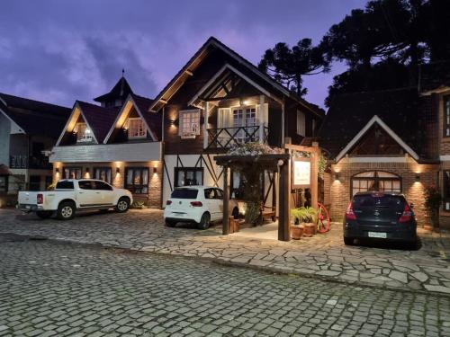 a house with two cars parked in front of it at Pousada Caliandra Da Serra in Canela