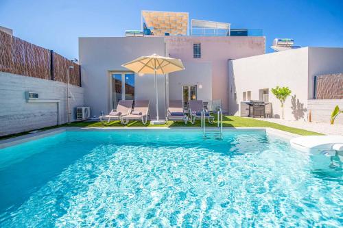 a pool with an umbrella and chairs and a house at Lemonia Plaka in Plaka