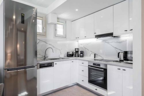 a kitchen with white cabinets and a stainless steel refrigerator at Lemonia Plaka in Plaka