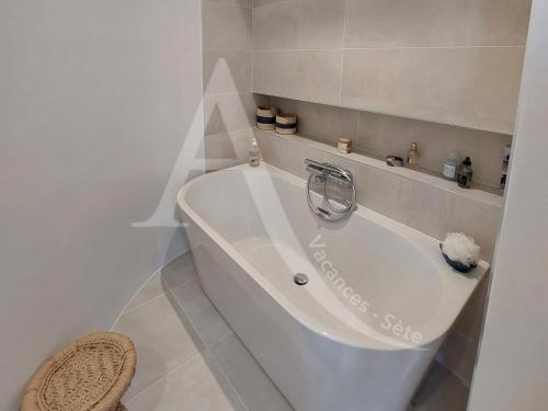 La salle de bains blanche est pourvue d'une baignoire blanche. dans l'établissement Super villa 6 personnes avec piscine et climatisation a cote des plages, à Sète